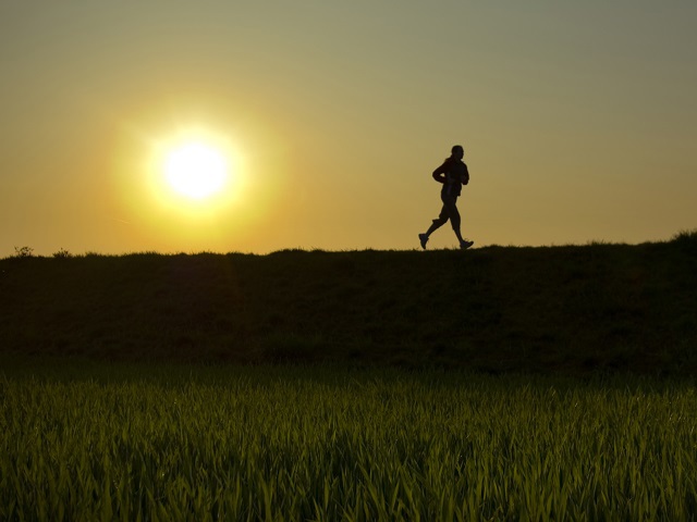 Silhouet van hardlopend persoon met ondergaande zon