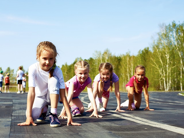 Vier kinderen op een rijtje van links naar rechts in start houding om te gaan hardlopen