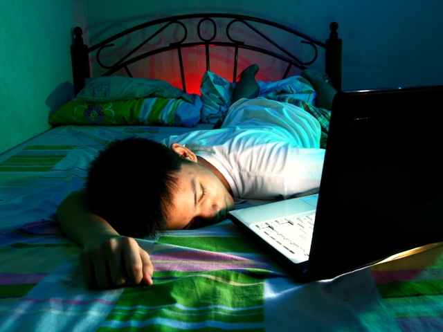 Kind op bed in slaap gevallen voor laptop
