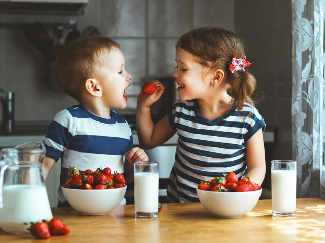 Twee kleine kinderen voeren elkaar aardbeien